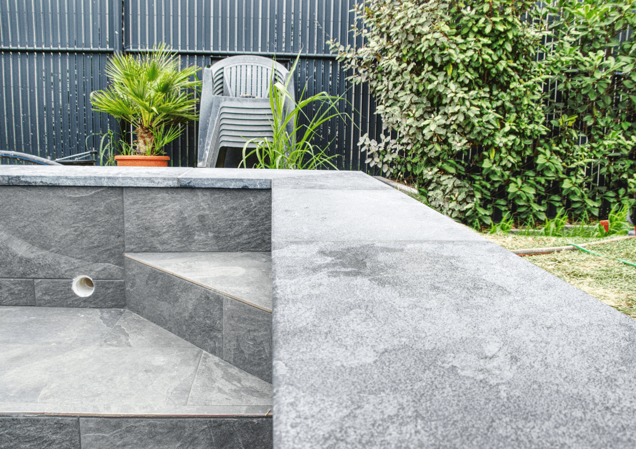 Détail de margelle de piscine et marches intérieures en carrelage effet pierre, avec joints époxy. Pose de précision réalisée par CCJ Carrelage dans le Gard.