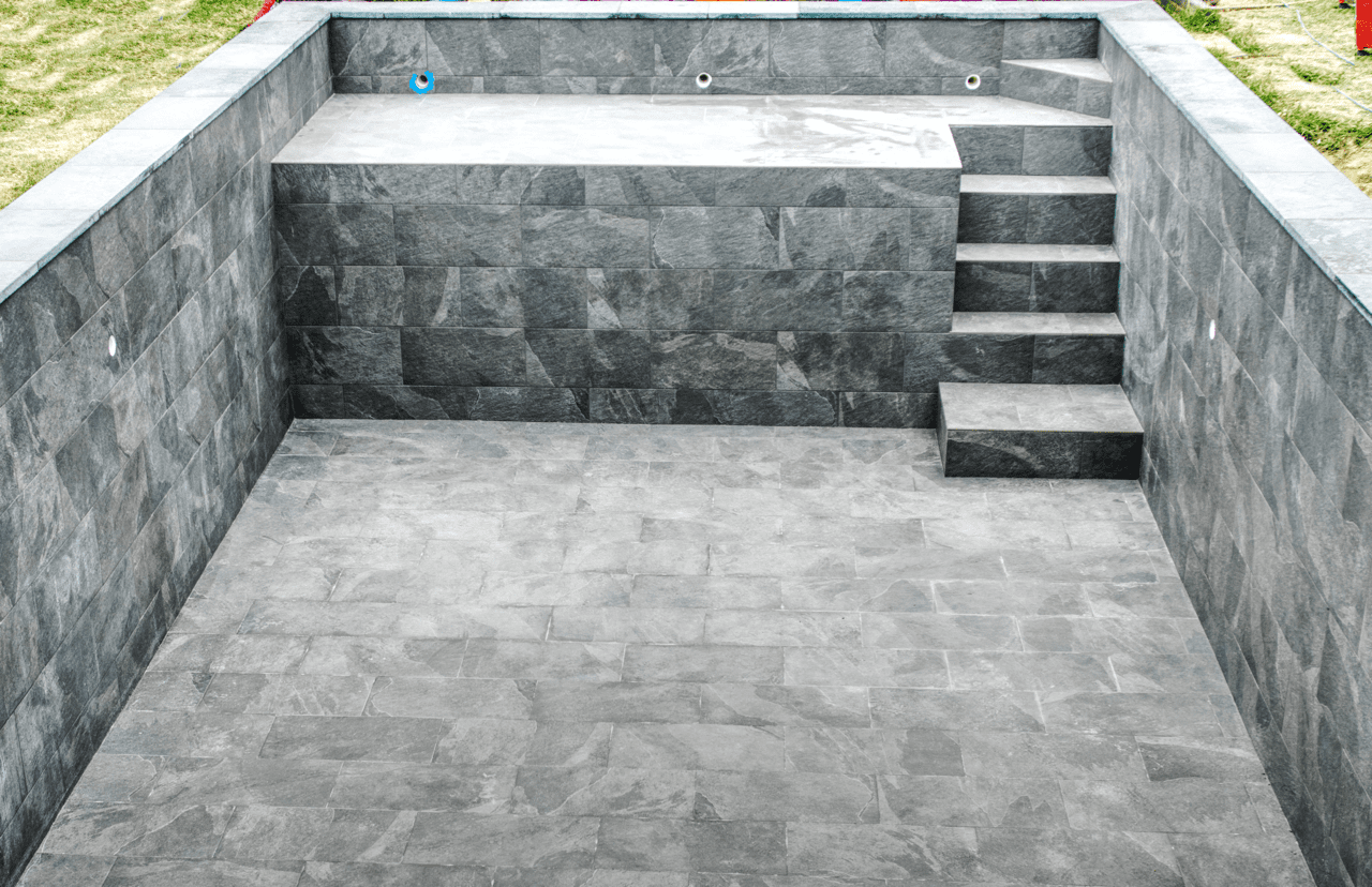Piscine carrelée avec carreaux 30x60 effet pierre et joints epoxy, réalisée par CCJ Carrelage à Montpellier. Escalier intégré et finitions modernes.