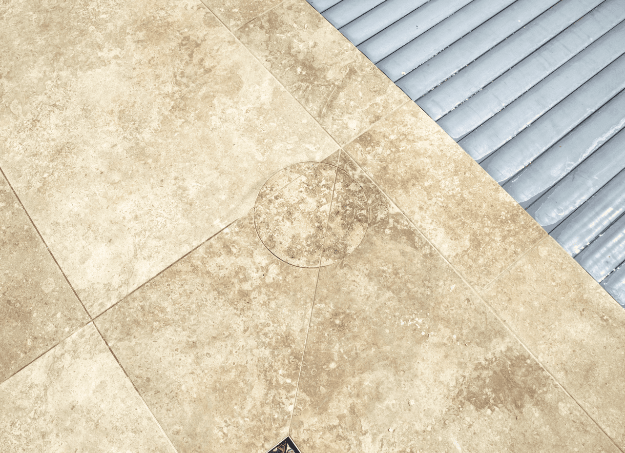 Trappe d’accès technique carrelée autour d’une piscine, parfaitement intégrée avec les dalles. Pose sur mesure réalisée par CCJ Carrelage à Montpellier (Hérault).